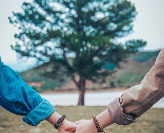 Dve osebi se držita za roke pred drevesom
